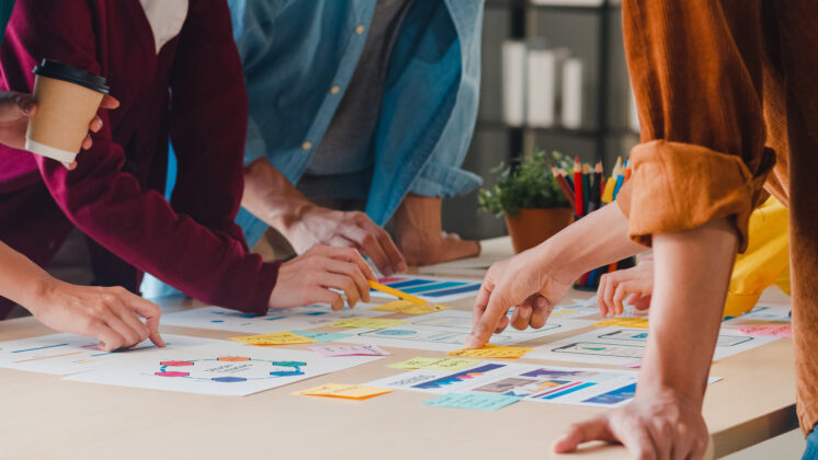 A team works over a table with colorful Post-Its, applying innovation through intrapreneurship