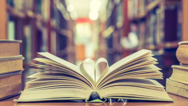 A book sits open in a library with two pages turned inward to form a heart