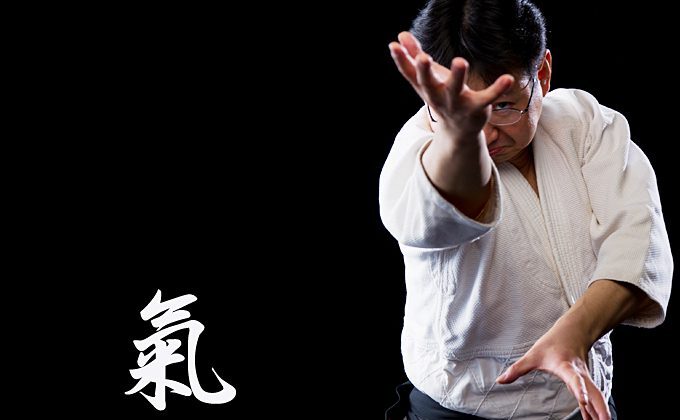 Tomoya Nakamura in aikido gear fiercely reaches for the camera with kanji beside him