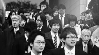 Unspoken Rules: How to Read the Air in Japanese Companies Black and white image of Japanese businessmen walking in a group, following unspoken rules of Japanese corporate culture