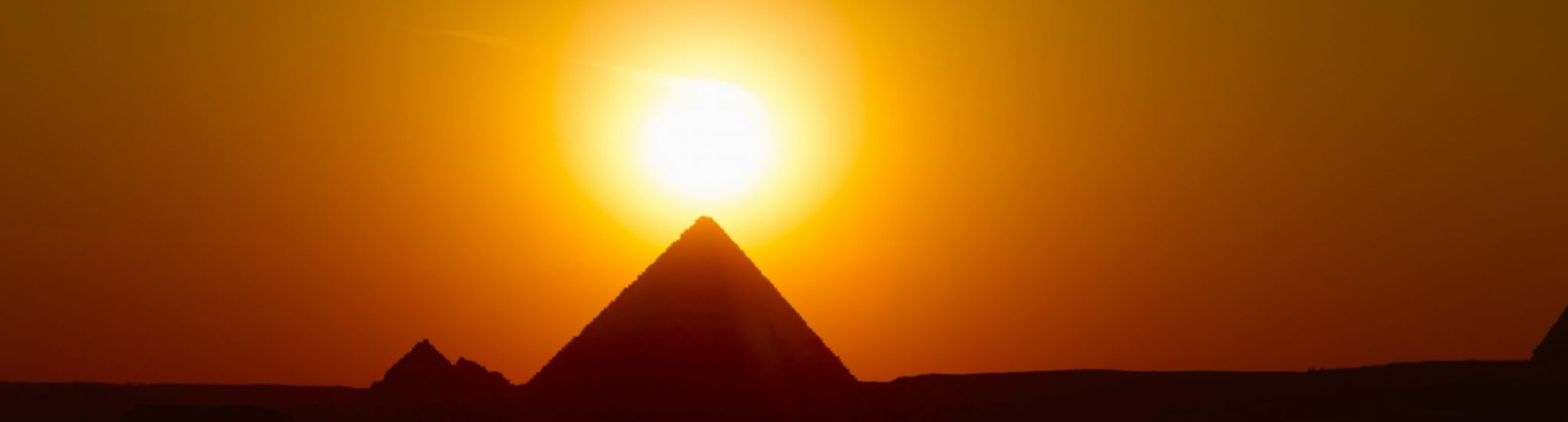A pyramid in Egypt with the sun setting behind it