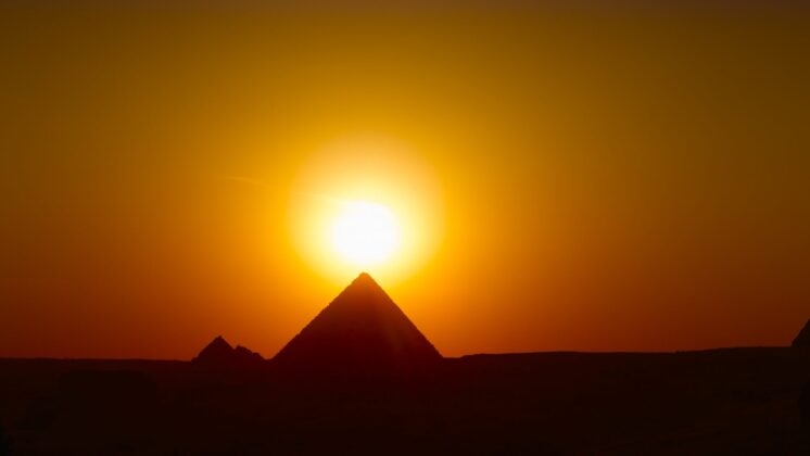 A pyramid in Egypt with the sun setting behind it
