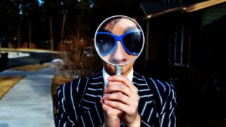 7 Presentation Skills to Give You an Edge in Your Next Job Interview Man holding up a large magnifying glass to his face
