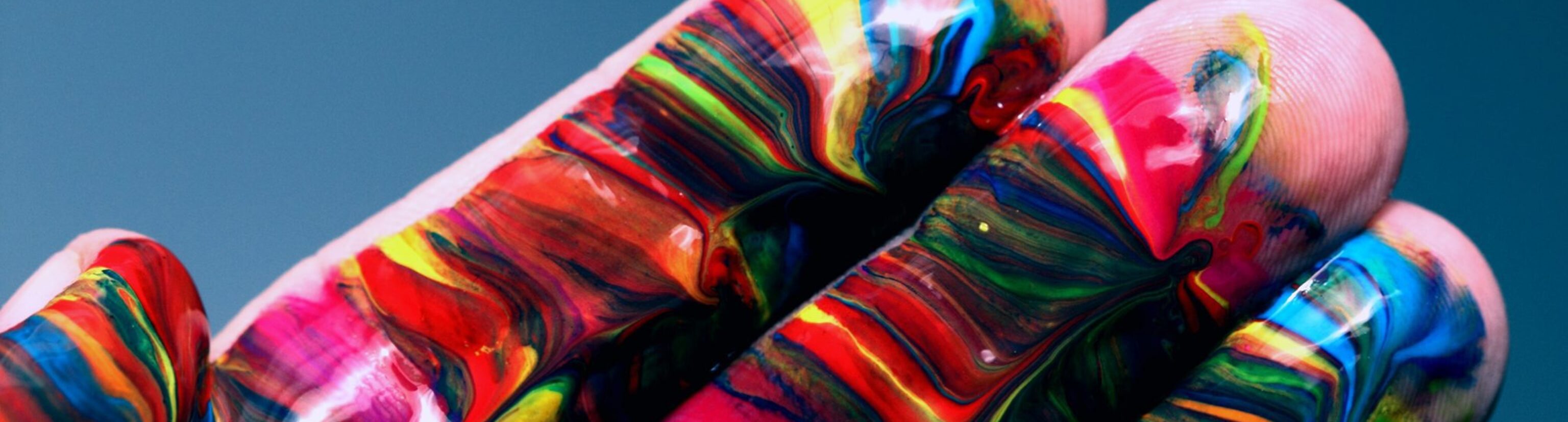 Image of a hand dipped in colorful swirls of paint, displaying both art and innovation