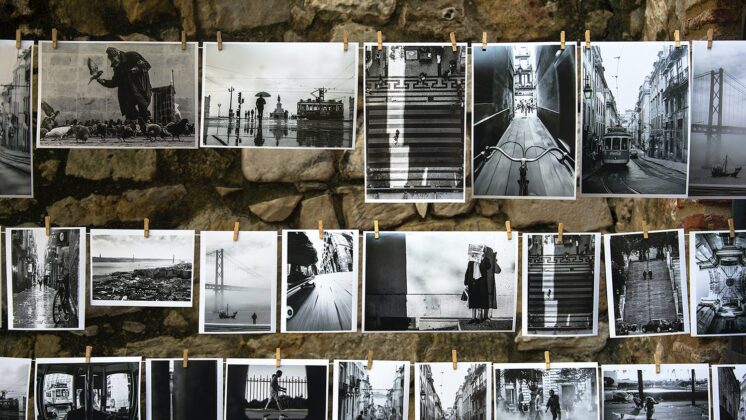 Both old and contemporary black and white photographs hang on a clothesline.