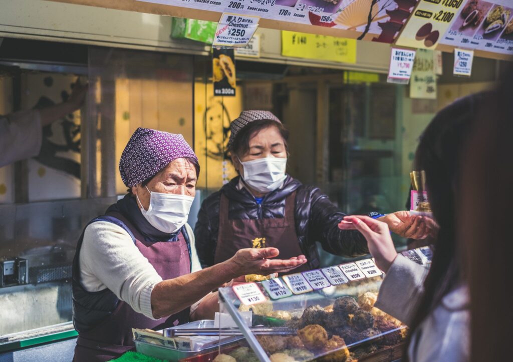 Japanese women wearing masks run a food stall