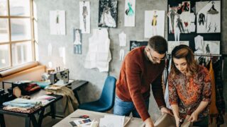 Supercharge Your Career with Empowerment Leadership Two tailors look over design plans.