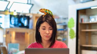 5 Reasons Remote Work Is the Ideal Creativity Incubator Image of a woman working on a laptop with a colorful chameleon on her head, suggesting creativity as she works remotely
