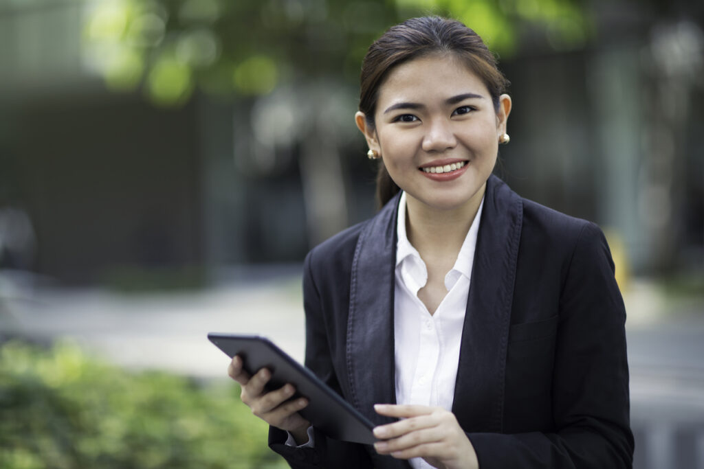 Filipina businesswoman holding a tablet and looking into the camera.