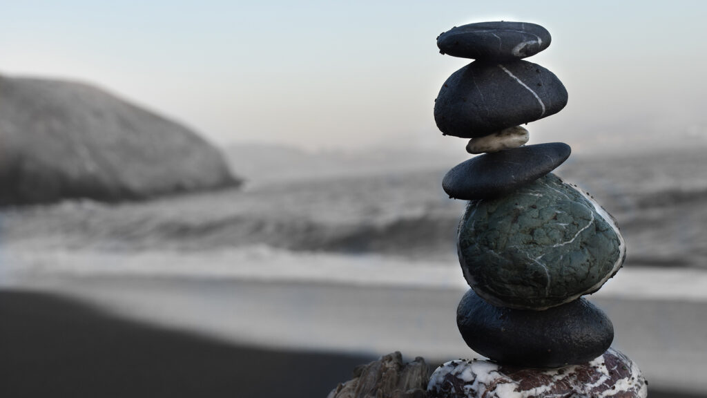 Zen rocks stacked with design thinking in front of a stormy shoreline