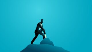 The Myth (and New Reality) of Managers and Leaders A businessman on a blue background braces himself to pull a sword from a stone, as in the Excalibur myth