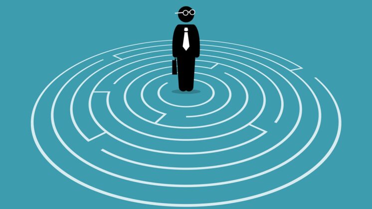 A businessman stands in a maze, showing how knowing if it's the right time to quit your job is partially about knowing the right path forward