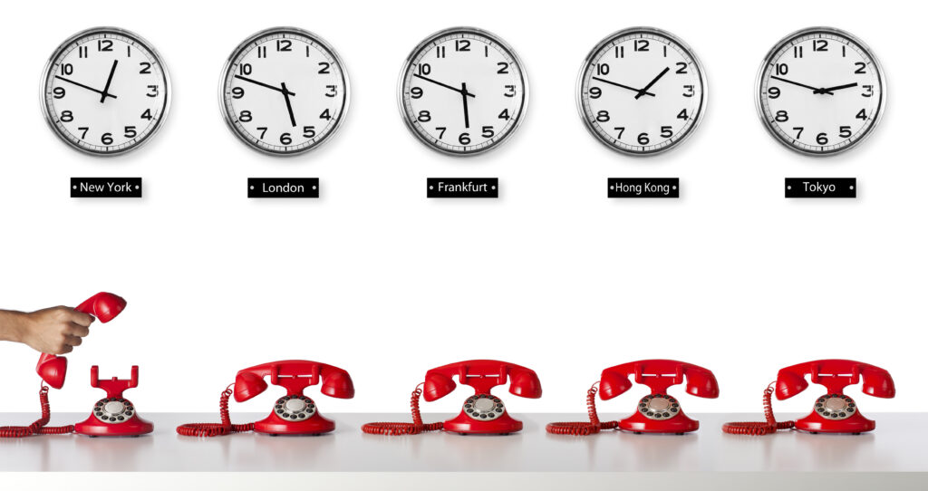 Clocks lined up on a wall show time zones above red phones