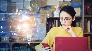 What We Learned about Remote Work in 2021 Woman does remote work in front of a laptop holding a phone