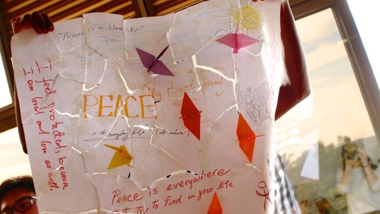 A boy holding up a poster promoting global peacebuilding initiatives.