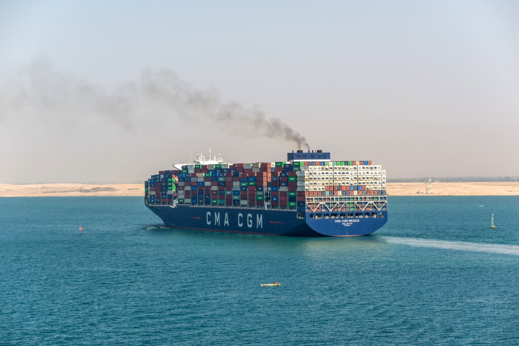 A container vessel belches pollution from its smokestack as it moves through the open ocean