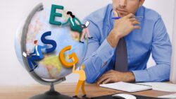 A businessman thinks about ESG strategy while staring at a globe with those letters superimposed on it