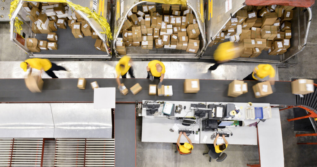 Blurred image of production line workers rushing to move boxes from a conveyer belt to a delivery truck