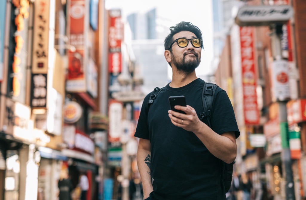 An Asian man using his smartphone for digital tourism.