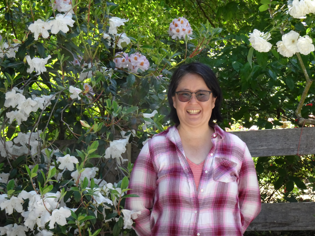 A photo of Ayako Lainez standing in front of flowers after learning to embrace empathy at work.
