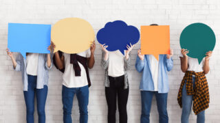 Why You Need Critical Thinking in a Diverse Workforce A diverse workforce stands against a blank wall with thought bubbles seeking the benefits of critical thinking