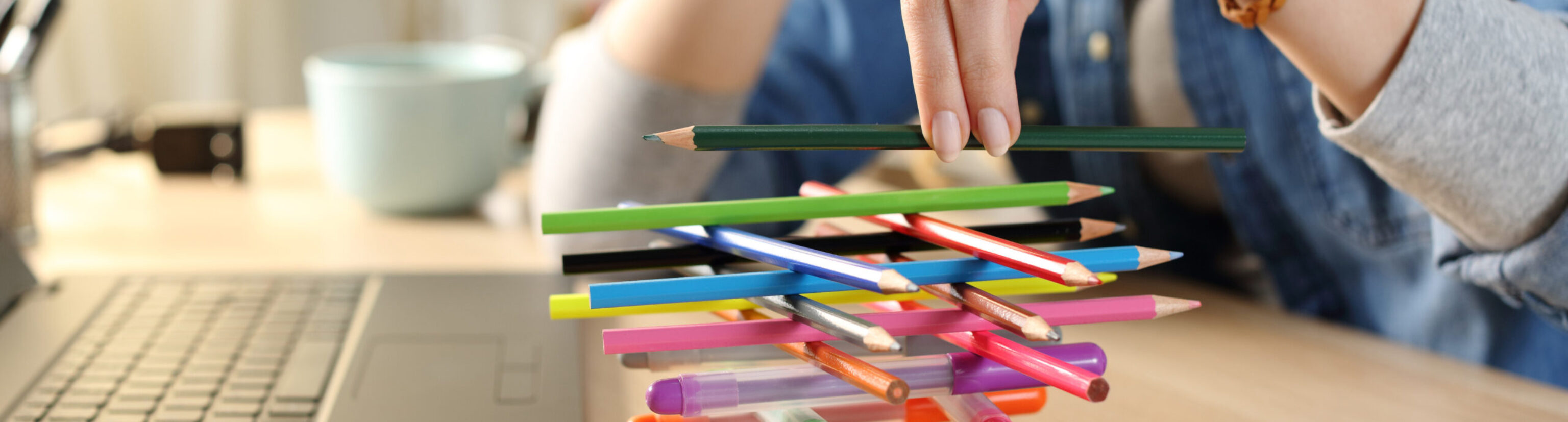 Bored woman at work in need of productivity tips builds a colorful stack of pens and pencils