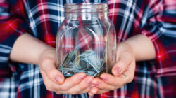 An entrepreneur holds a glass jar of startup capital with both hands