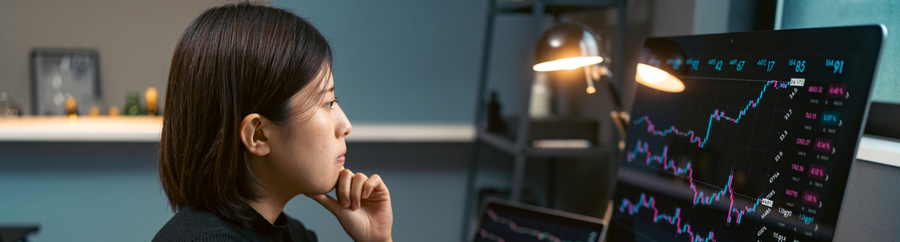 A young woman is doing cryptocurrency business trading on her computer at home at nigh.