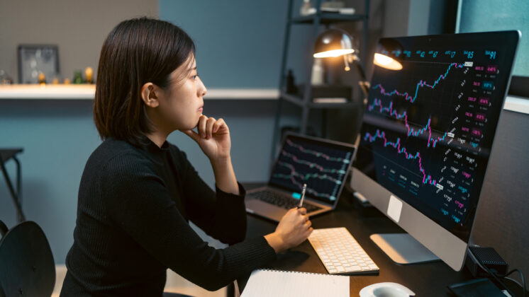 A young woman is doing cryptocurrency business trading on her computer at home at nigh.