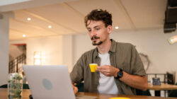 One adult modern man caucasian male with beard and mustaches wear causal shirt working remote from cafe freelance work or blog checking online content or browsing internet while sitting alone